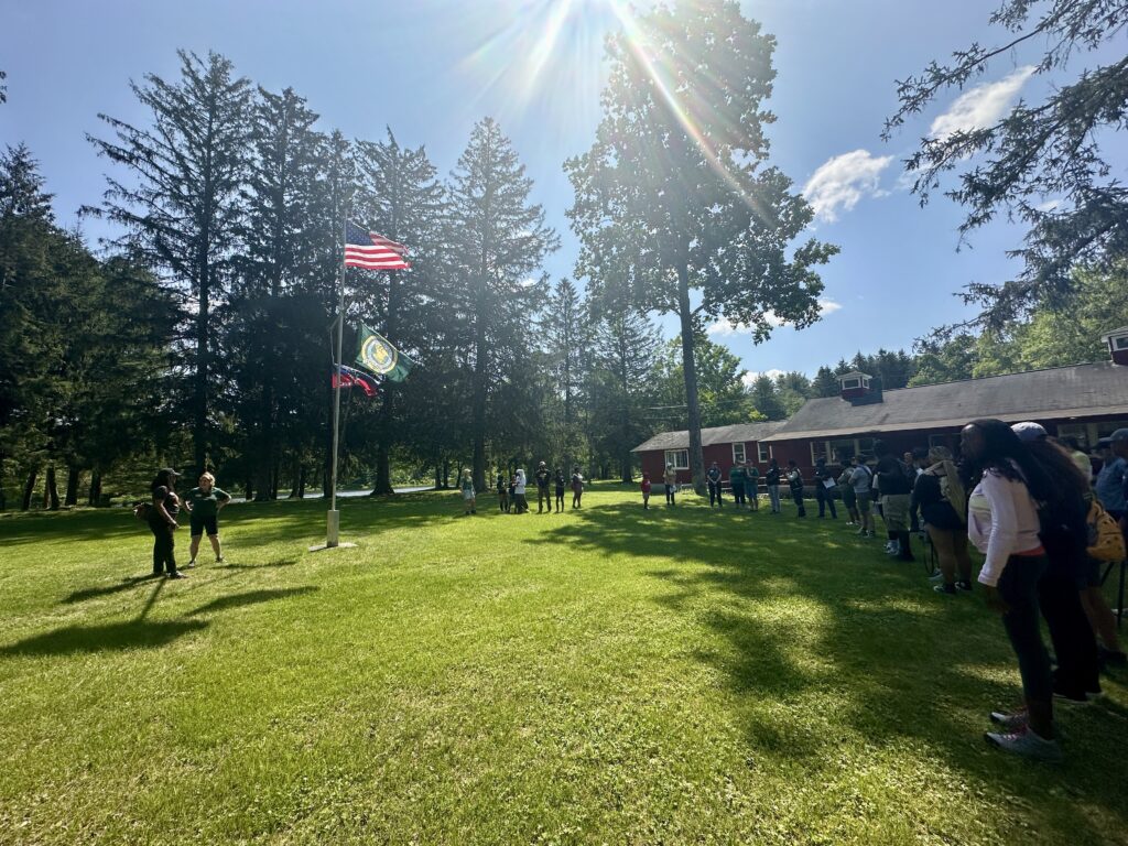 Juneteenth participants gathered around flag pole and CCC statue, in front of Long House.